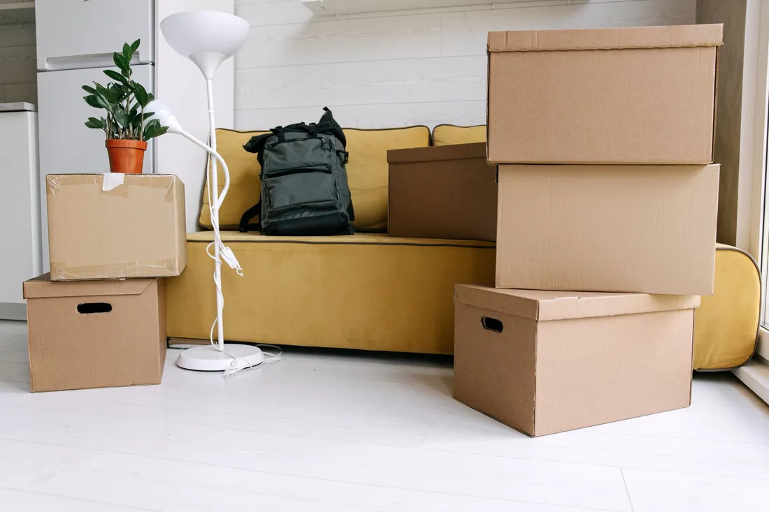 Gepackte Umzugskartons stehen im Wohnzimmer bereit